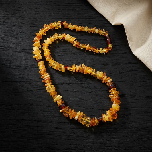 Collier en ambre naturel de la Baltique posé à plat sur une surface en bois noir texturé. Perles irrégulières.
